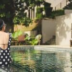 woman sitting beside pool near house during daytime