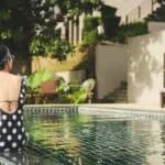 woman sitting beside pool near house during daytime