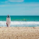 white surfboard vertically standing on seashore