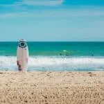 white surfboard vertically standing on seashore