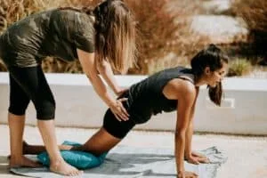 femme en débardeur noir et short noir agenouillée sur un tapis