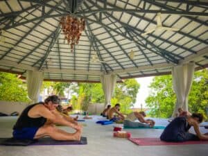 A diverse group of people practicing yoga in a tranquil open-air pavilion, focusing on health and wellness.