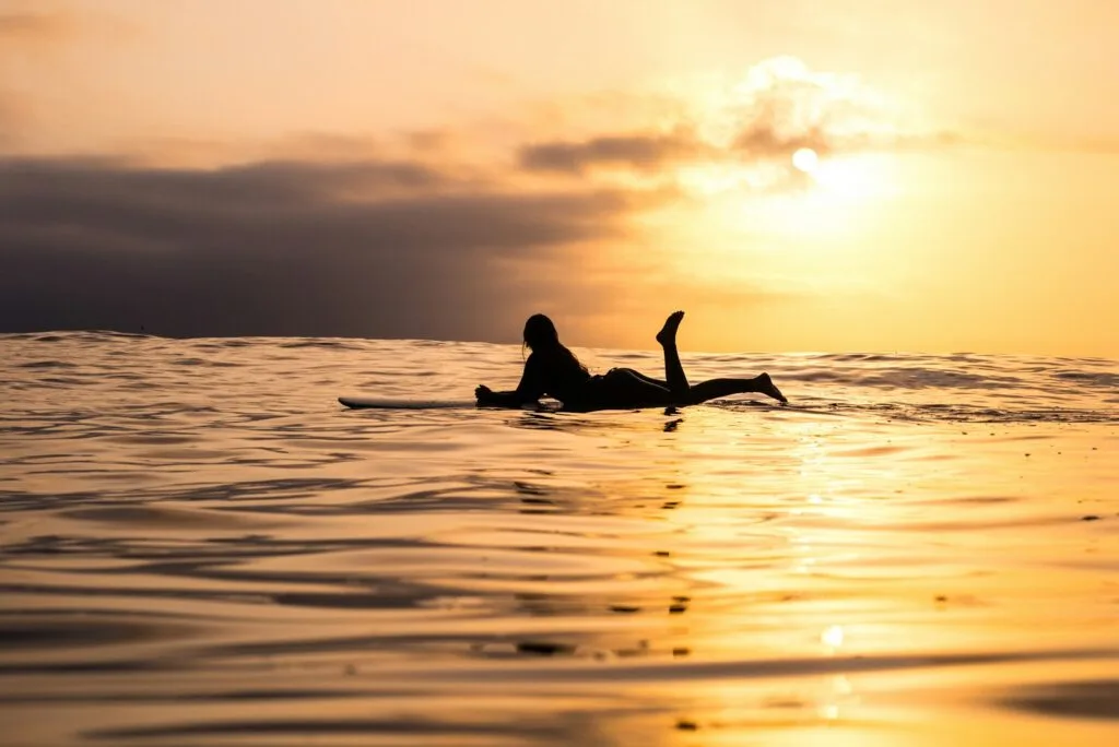 silhouette d'une femme allongée sur une planche de surf à la mer
