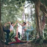 three women doing yoga at forest
