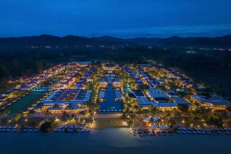 Aerial night view of illuminated resort by beach.