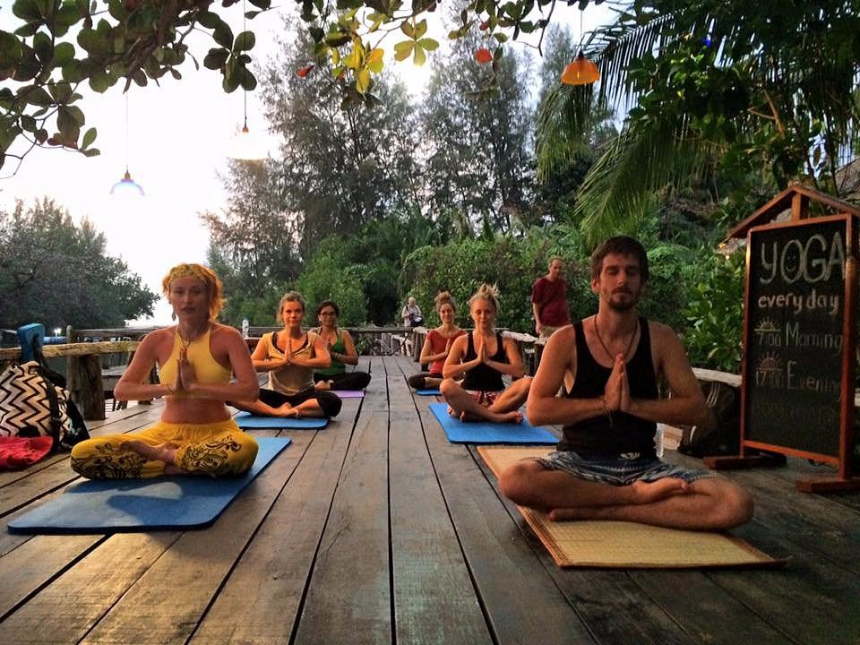 Group outdoor yoga session on wooden deck.