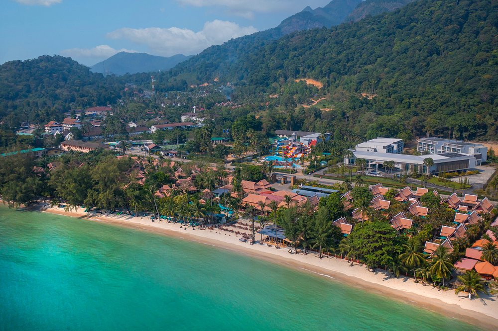 Aerial view of beachfront resort and lush mountains.