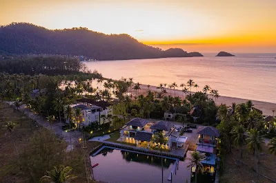 Tropical beach resort at sunset with mountains