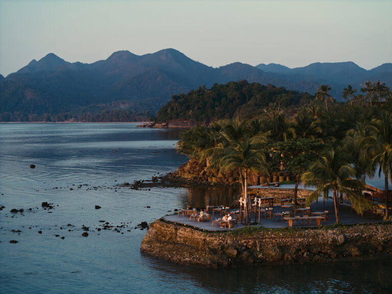 Scenic island resort with palm trees and mountains.