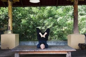 Woman performing advanced yoga pose on wooden platform