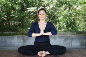 Woman meditating outdoors with hands in prayer position