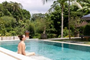 Woman relaxing by tropical resort swimming pool