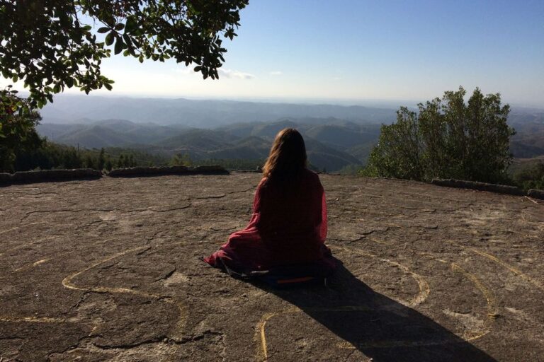 Person sitting on cliff overlooking mountain landscape