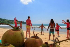 Group stretching on beach with coconuts foreground