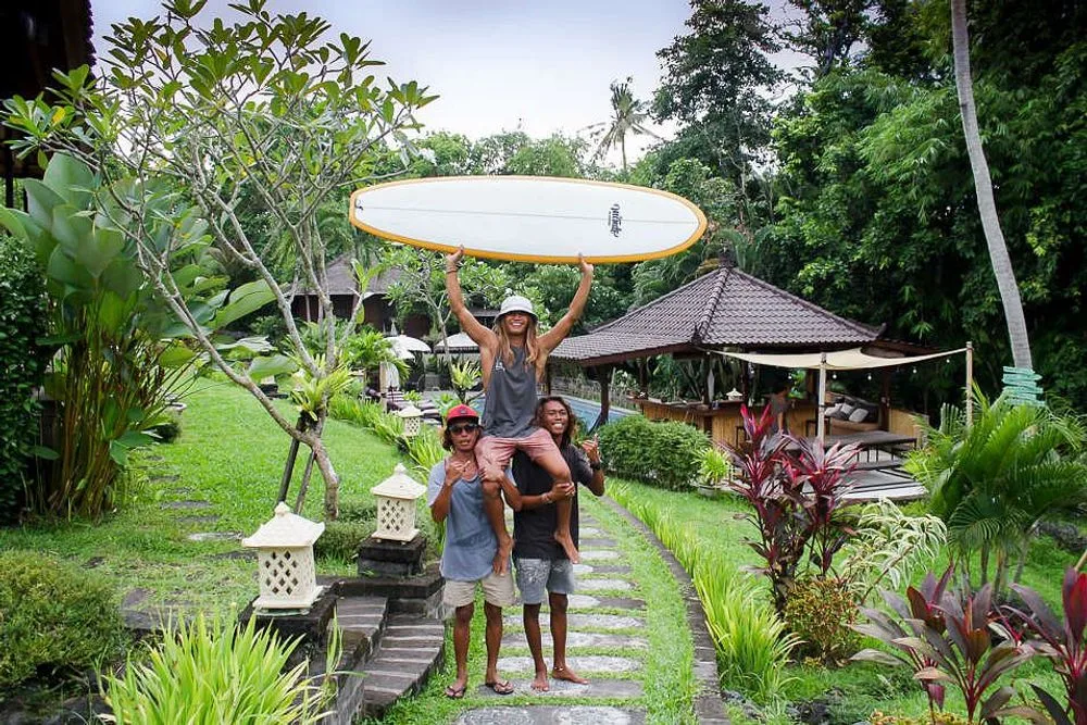 Friends holding surfboard in tropical garden resort