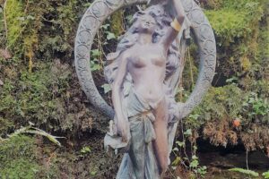 Bronze statue of nude woman in garden