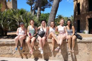 Six women sitting on stone wall outdoors