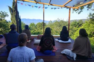 Group meditating on deck overlooking mountains