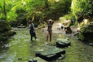 Two women standing in shallow forest stream