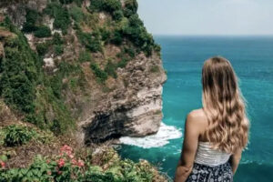 Woman overlooking turquoise ocean from cliffside viewpoint