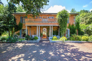 Elegant two-story villa with columns and lush garden