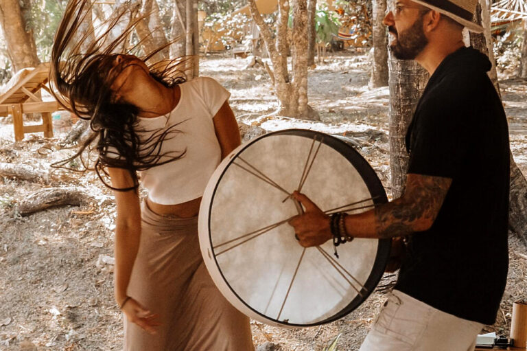 Woman dancing beside man playing drum outdoors
