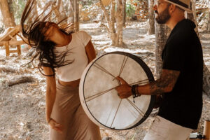Woman dancing while man plays frame drum outdoors
