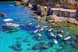 Group paddleboarding in clear turquoise coastal waters