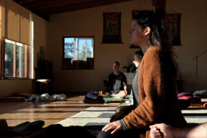 People meditating in sunlit yoga studio