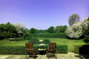 Two wooden chairs overlooking lush garden lawn