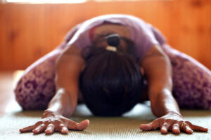 Person practicing child’s pose yoga on mat