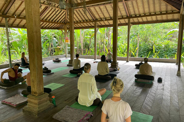 People meditating in open-air jungle yoga pavilion