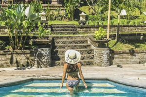 Woman in hat entering tropical garden pool