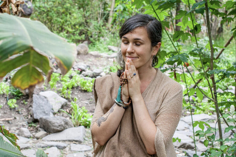 Woman meditating with hands in prayer outdoors