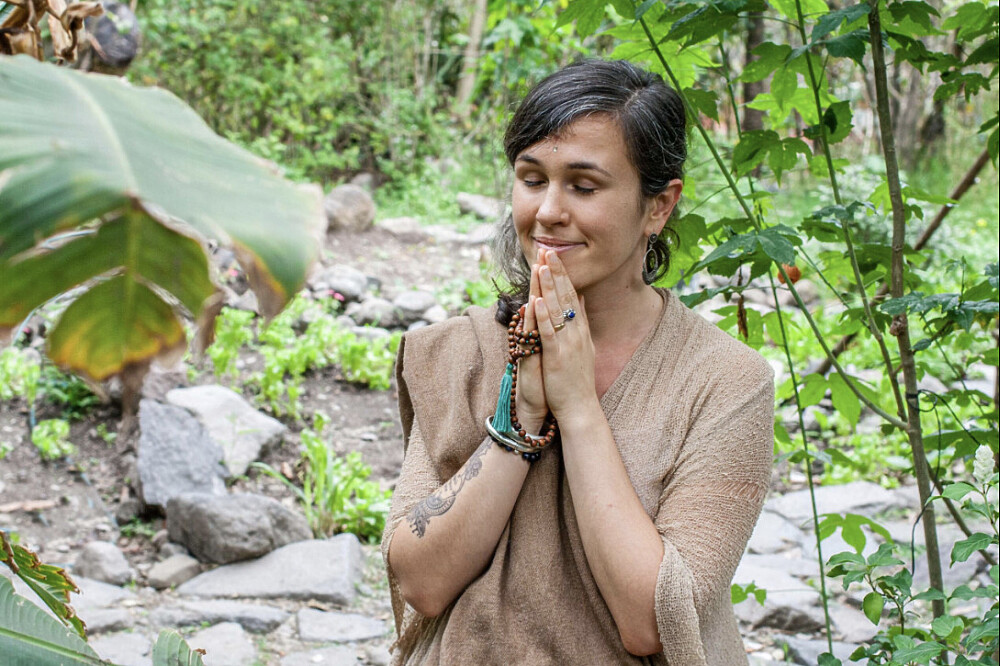 Woman meditating with hands in prayer outdoors
