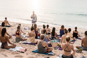 Beach yoga class at sunrise by ocean