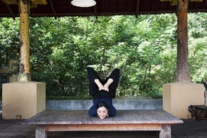 Woman performing advanced yoga pose on wooden platform