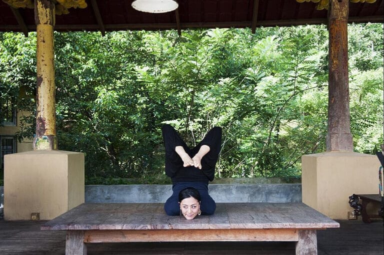Woman performing advanced yoga pose on wooden platform