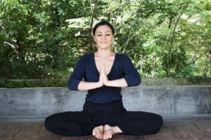 Woman meditating outdoors in prayer pose