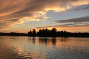 Sunset over calm lake with tree silhouettes