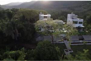 Modern white villas on lush hillside at sunset