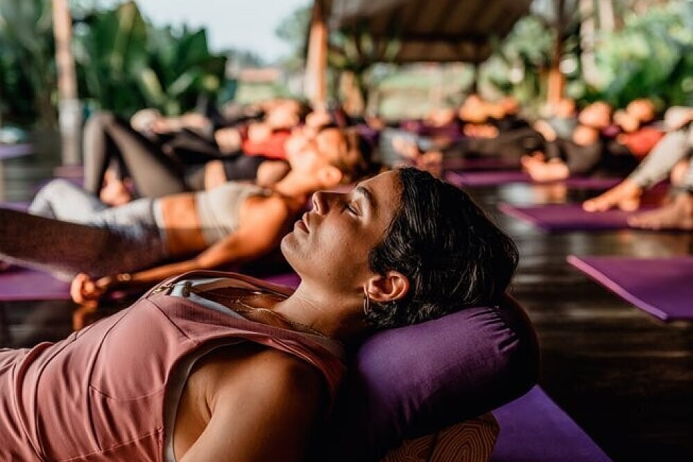 Woman resting on bolster during yoga class