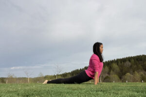 Woman practicing upward dog yoga on grass