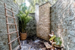 Outdoor stone shower with tropical plants and ladder