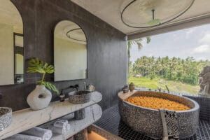Luxury bathroom with terrazzo tub overlooking tropical landscape
