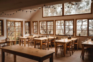 Sunlit rustic classroom with wooden tables and large windows