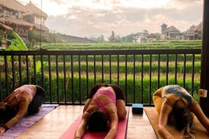 Three women practicing yoga overlooking rice terraces