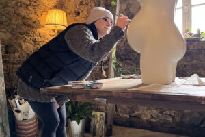 Artist painting torso sculpture in rustic studio