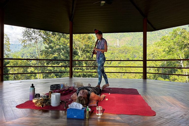 Woman performing sound healing over person on mat