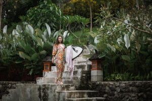 Woman holding surfboard on tropical garden steps